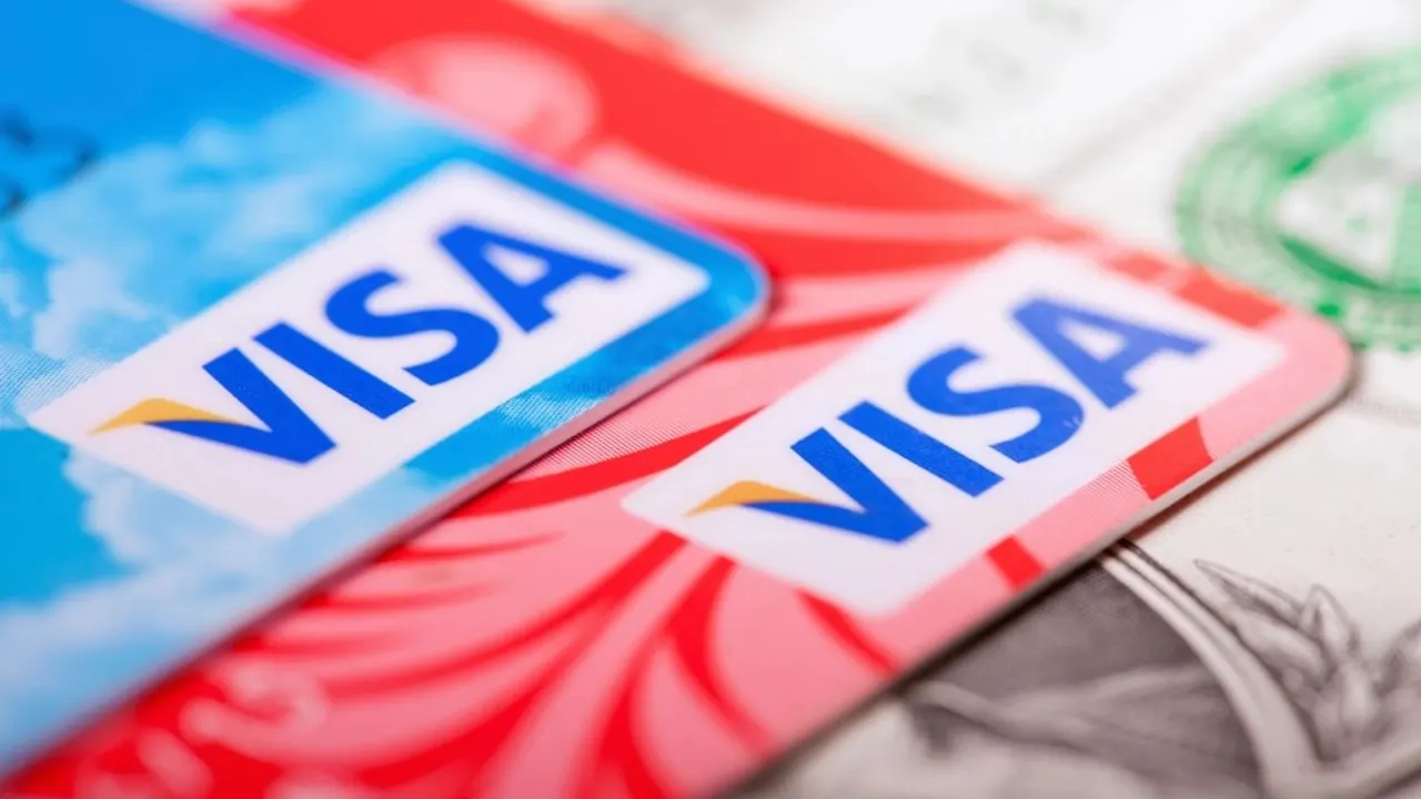 Credit card held in front of a laptop checkout page