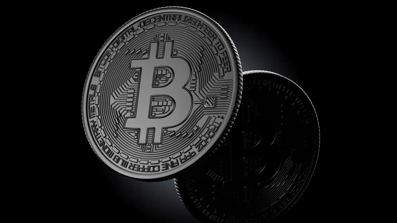 Phone with a cryptocurrency wallet app next to a bitcoin coin